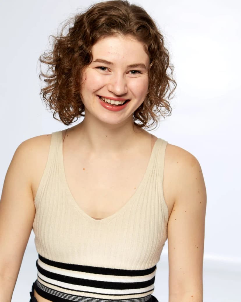 Claire Sersun smiling, wearing a cream-colored top with black stripes